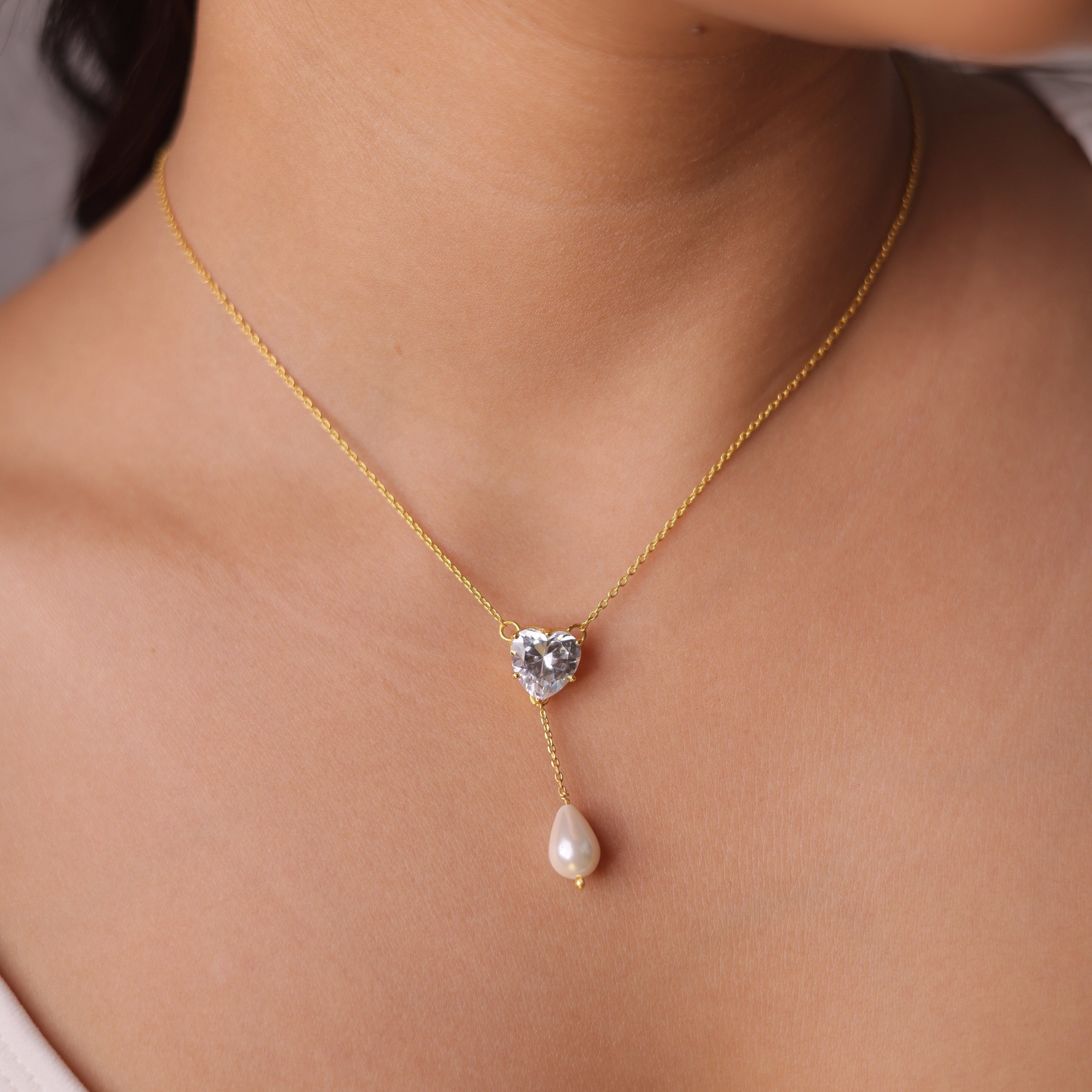 Necklace with heart-shaped pendant and pearl drop worn by a person